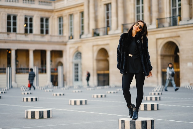 stilvolles Mädchen, das durch die Straßen von Paris während des Frühlinges geht