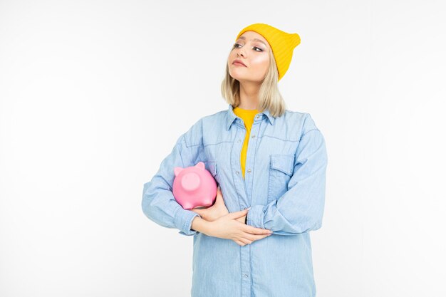 Stilvolles Mädchen in einem blauen Hemd mit einer Bank zum Sparen von Finanzen auf einem Weiß mit Kopienraum