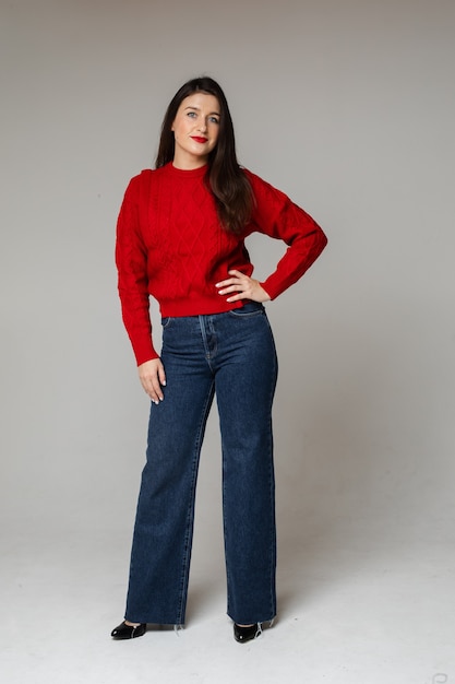 Stilvolles Mädchen in rotem Pullover und Jeans.