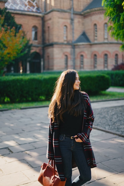 stilvolles Mädchen, welches die Stadt und den Park im Herbst erforscht