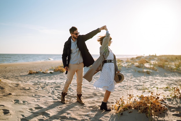 Stilvolles Paar, das am Meer spazieren geht und sich umarmt Schönes Hipster-Paar genießt die gemeinsame Zeit