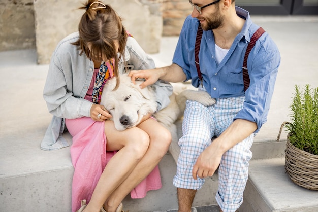 Stilvolles Paar hat Spaß und sitzt mit seinem Hund auf einer Straße