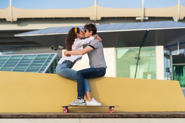 Stilvolles Paar küssen im Skatepark sitzen junge süße Longboarder Mann und Frau in Liebe Kuscheln