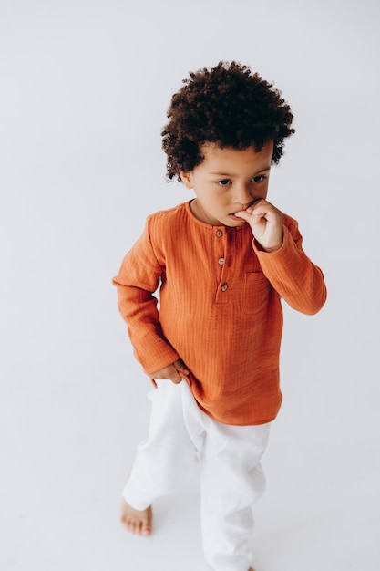 Stilvolles Porträt eines lockigen, dunkelhäutigen 3-jährigen Jungen in stilvoller Leinenkleidung