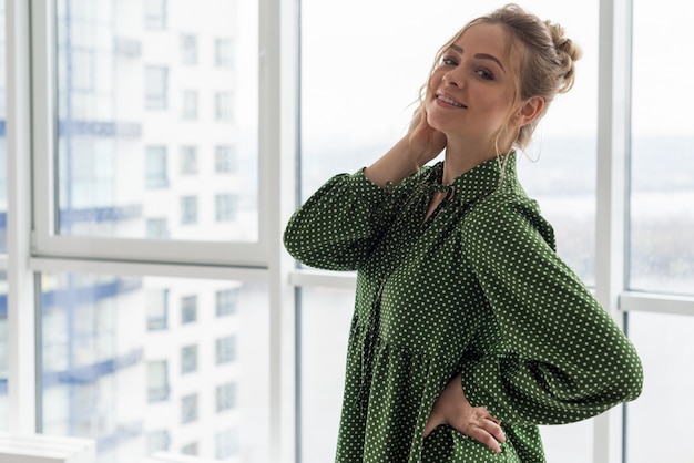 Stilvolles schönes blondes Mädchen in einem Wolkenkratzer im Büro vor dem hintergrund des Fensters