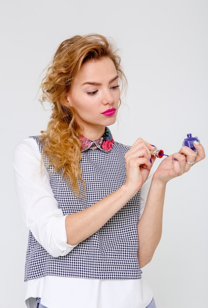 Stilvolles schönes Mädchen mit langem Haar färbt Nagellack