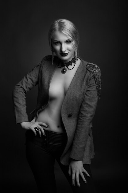 Stilvolles Schwarz-Weiß-Studioporträt einer sexy blonden Frau mit hellem Make-up trägt eine Jacke auf einem nackten Körper