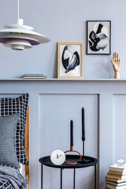 Stilvolles skandinavisches Schlafzimmerinterieur mit Design-Couchtisch, Posterrahmen, Buch, Uhr, Dekoration, persönlichem Zubehör, schönen Bettwäsche, Decken und Kissen.