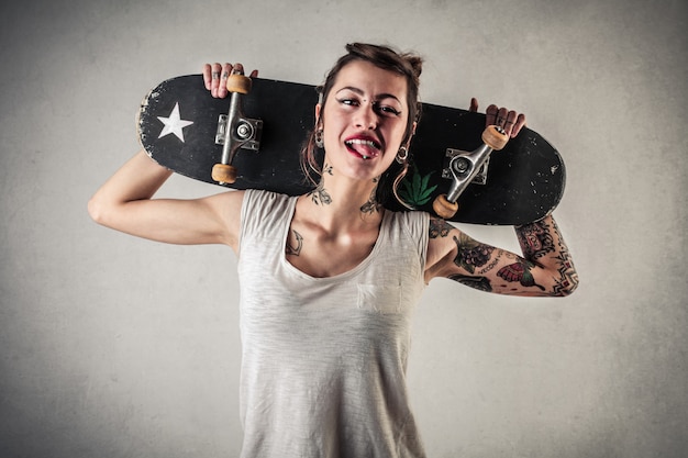 Stilvolles tätowiertes Mädchen mit einem Skateboard