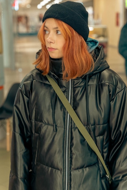 Foto stilvolles teenagermädchen mit roten haaren in schwarzem strickhut und jacke vertikalportrait