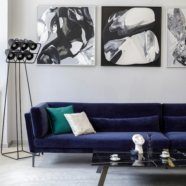 Stilvolles und modernes Wohnzimmer-Interieur mit blauem Samt-Sofa Mock-up-Gemälde Design schwarze Lampe Pflanze Tischdekoration Betonboden elegante persönliche Accessoires in Wohnkultur