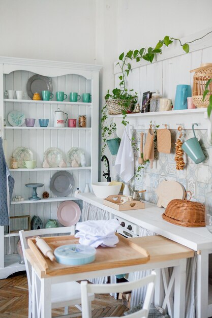 Stilvolles und sonniges Interieur des Küchenraums mit kleinem Holztisch im Fotostudio. Skandinavische Raumdekoration mit Küchenzubehör.