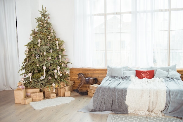 Stilvolles Zimmerinterieur mit schönem Weihnachtsbaum und Geschenkboxen