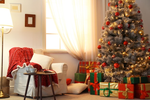 Stilvolles Zimmerinterieur mit wunderschönem Weihnachtsbaum und Geschenkboxen