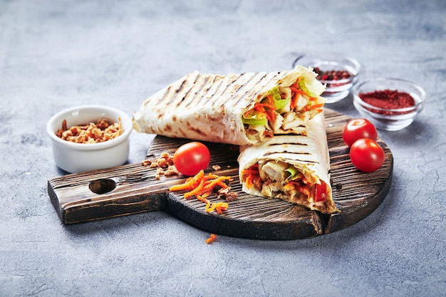 Östliches traditionelles Döner mit Huhn und Gemüse, Döner Kebab mit Saucen auf Holzschneidebrett. Fast Food. Östliches Essen.