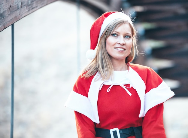 Stock Foto von Mama Noel posiert glücklich mit dem roten Kleid auf einer Holzbrücke Weihnachtszeit