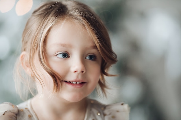 Stockfoto-Kopfschuss des reizenden brünetten Mädchens im festlichen Kleid auf unscharfem Hintergrund. Entzückendes junges Mädchen, das weg in der Nahaufnahme lächelt.