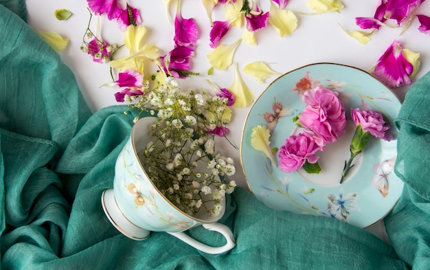 Stoff, Tasse und natürliche Blumen und Blütenblätter