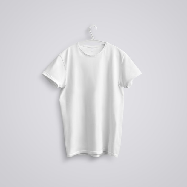 Stoff-Vorlage. Ein leeres T-Shirt mit Schatten auf einem weißen Plastikbügel auf Studiohintergrund. Vordere Stellung. Mockup, das in Ihrem Design verwendet werden kann