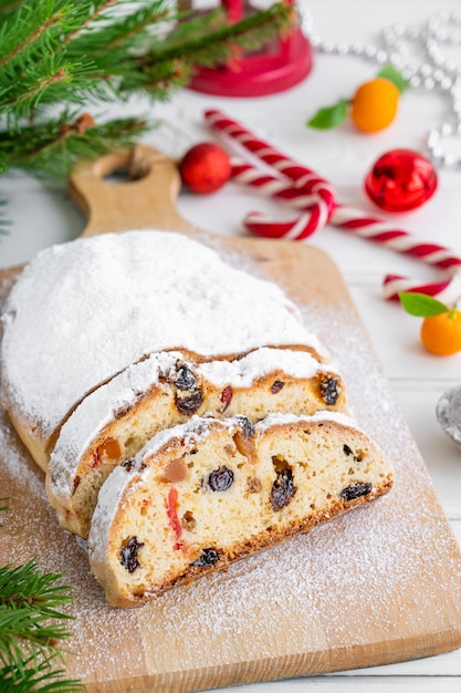 Stollen de Natal com frutas secas e açúcar de confeiteiro em um quadro sobre um fundo branco de madeira