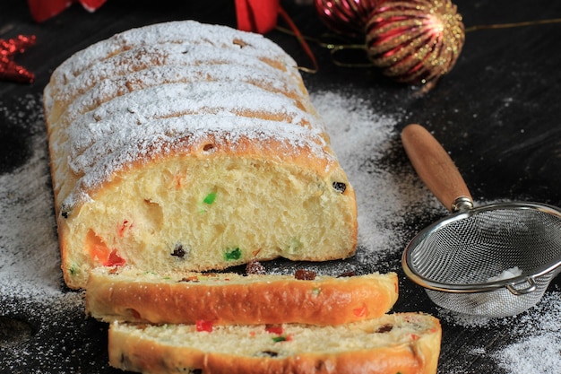 Stollen de Navidad. Pan de fruta dulce tradicional con azúcar glas. Ajuste de la mesa navideña, decorada con un mini árbol y decoración navideña.