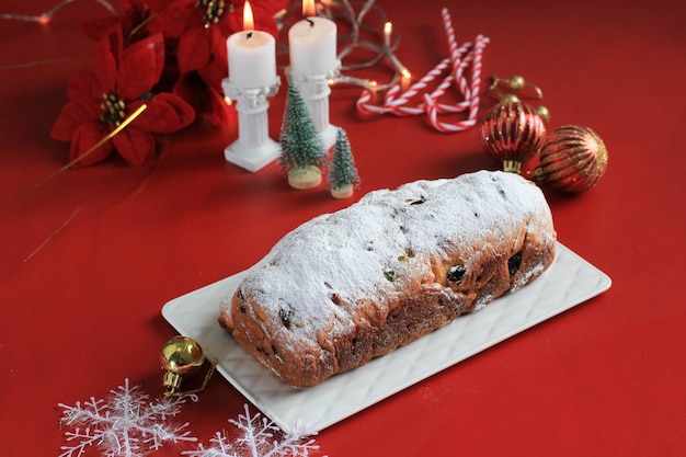 Stollen de Navidad sobre fondo rústico. Postre de repostería tradicional navideña de Alemania. Stollen para Navidad, concepto rojo