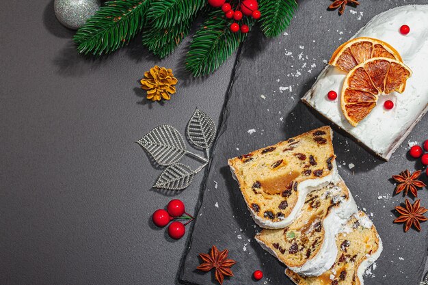 Stollen tradicional bolo alemão pastelaria europeia perfumado pão caseiro com especiarias e frutas secas galhos de árvores de Natal e decorações fundo preto vista superior