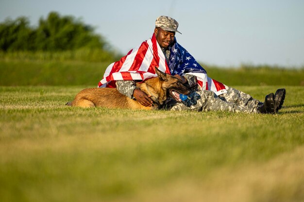 Stolz auf ihr Land. Soldat mit US-Flagge bedeckt, der mit Militärhund auf Gras spielt