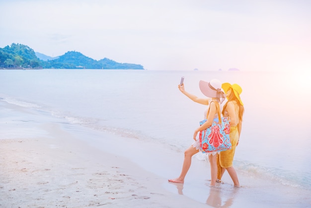 Stolz und LGBTQ+ am Sommerstrand. Bisexuelle und homosexuelle Liebespaare. Verwenden Sie das Smartphone für das Aufgabenfoto.