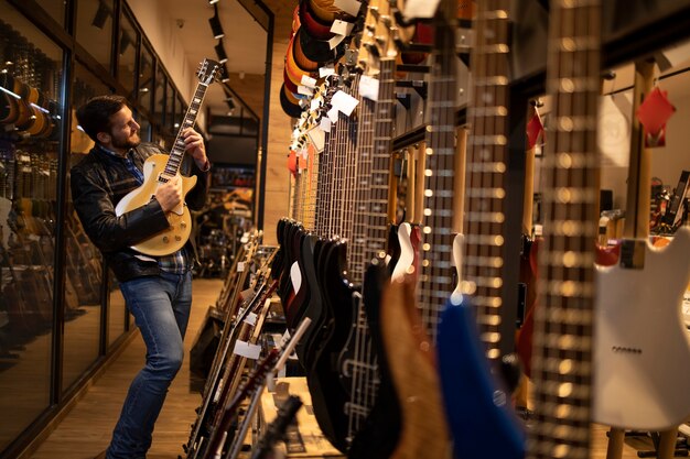 Stolzer junger Rockermusiker in Lederjacke, der im Musikladen E-Gitarre spielt.