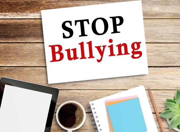 Stop Bullying Text en el cuaderno con lápiz y tableta en el fondo de la mesa de madera