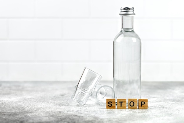 Stoppen Sie das Alkoholismus-Konzept Alkoholabhängigkeit Glasflasche Wodka Tequila und leeres Schnapsglas