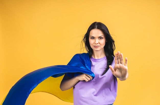 Stoppen Sie den Krieg in der Ukraine Porträt einer traurigen, aggressiven, wütenden Frau, die die ukrainische Flagge in den Händen hält