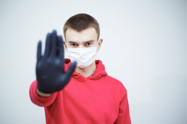 Stoppen Sie die Verbreitung von COVID-19. Mann mit Maske und Handschuhen, die Stoppsymbol zeigen. Pandemisches weltweites Problem. Symbol für Schutz und Verantwortung.