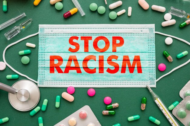 Stoppen Sie Rassismus-Text auf einem grünen Gesundheitshintergrund der medizinischen Maske