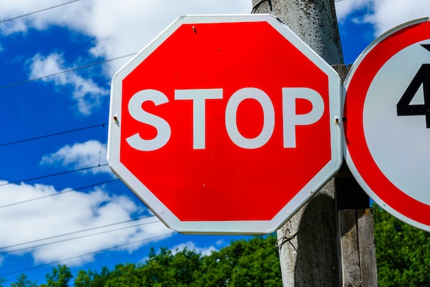 Stoppschild an einem Pfosten am Straßenrand gegen blauen Himmel