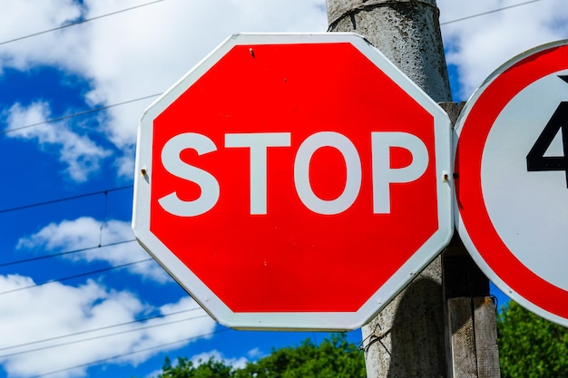 Stoppschild an einem Pfosten am Straßenrand gegen blauen Himmel