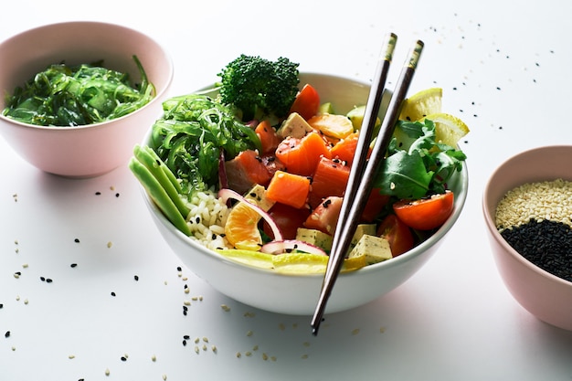 Stoßschüssel mit Lachsen, Avocado, Gurken, Arugula, lokalisiert über weißem Hintergrund.