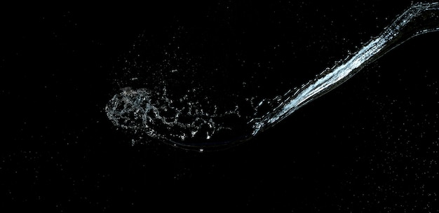 Strahl aus transparentem Wasser mit kleinen Tropfen und Spritzern auf schwarzem Hintergrund