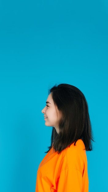 Strahlende junge Frau in stilvoller orangefarbener Kleidung, lächelnd mit einem strahlenden, zahnigen Lächeln im Profil
