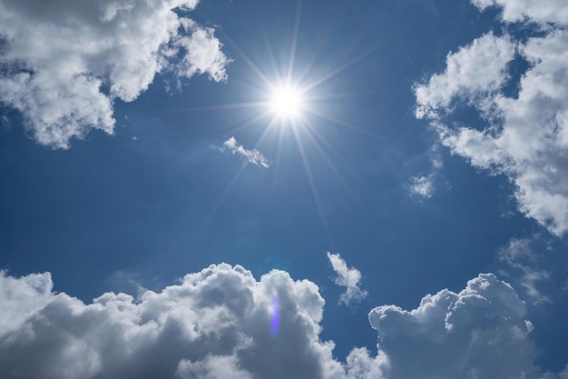 Strahlende Sonne am klaren blauen Himmel mit Lens Flare des Sonnenlichts am Himmelshintergrund Helle Sonne am blauen Himmel weiße Wolken Natur und Umwelt Hintergrund.