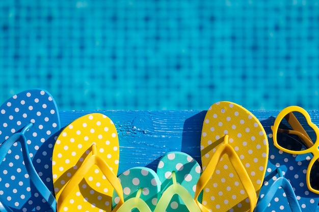 Strand-Flipflops und Sonnenbrillen auf blauem Holz vor Wasserhintergrund