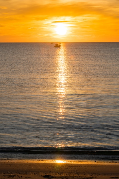 Strand, Meer während des Sonnenaufgangs der Sommersaison morgens mit Fischerboot des Schattenbildes.