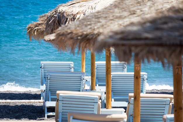 Strand mit Sonnenschirmen und Liegestühlen am Meer in Santorini