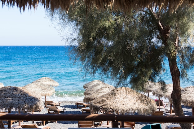 Strand mit Sonnenschirmen und Liegestühlen am Meer in Santorini