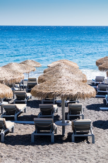 Strand mit Sonnenschirmen und Liegestühlen in Santorini