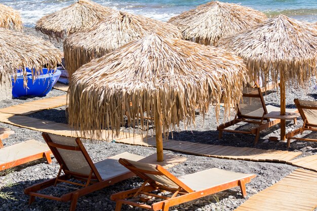 Strand mit Sonnenschirmen und Liegestühlen in Santorini