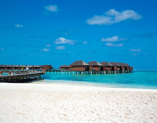 Strand mit Wasserbungalows auf den Malediven Blaues Meer und blauer Himmel