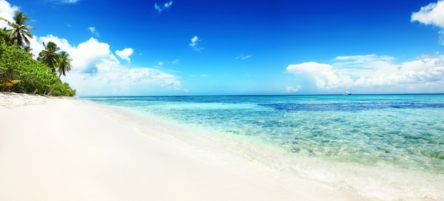 Strand mit weißem Sand, Sonne und ruhigem Meer. Tropisches Banner.