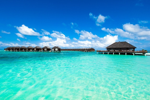 Strand mit weißem Sand, türkisfarbenem Meerwasser und blauem Himmel mit Wolken an sonnigen Tagen Natürlicher Hintergrund für Sommerferien Panoramablick